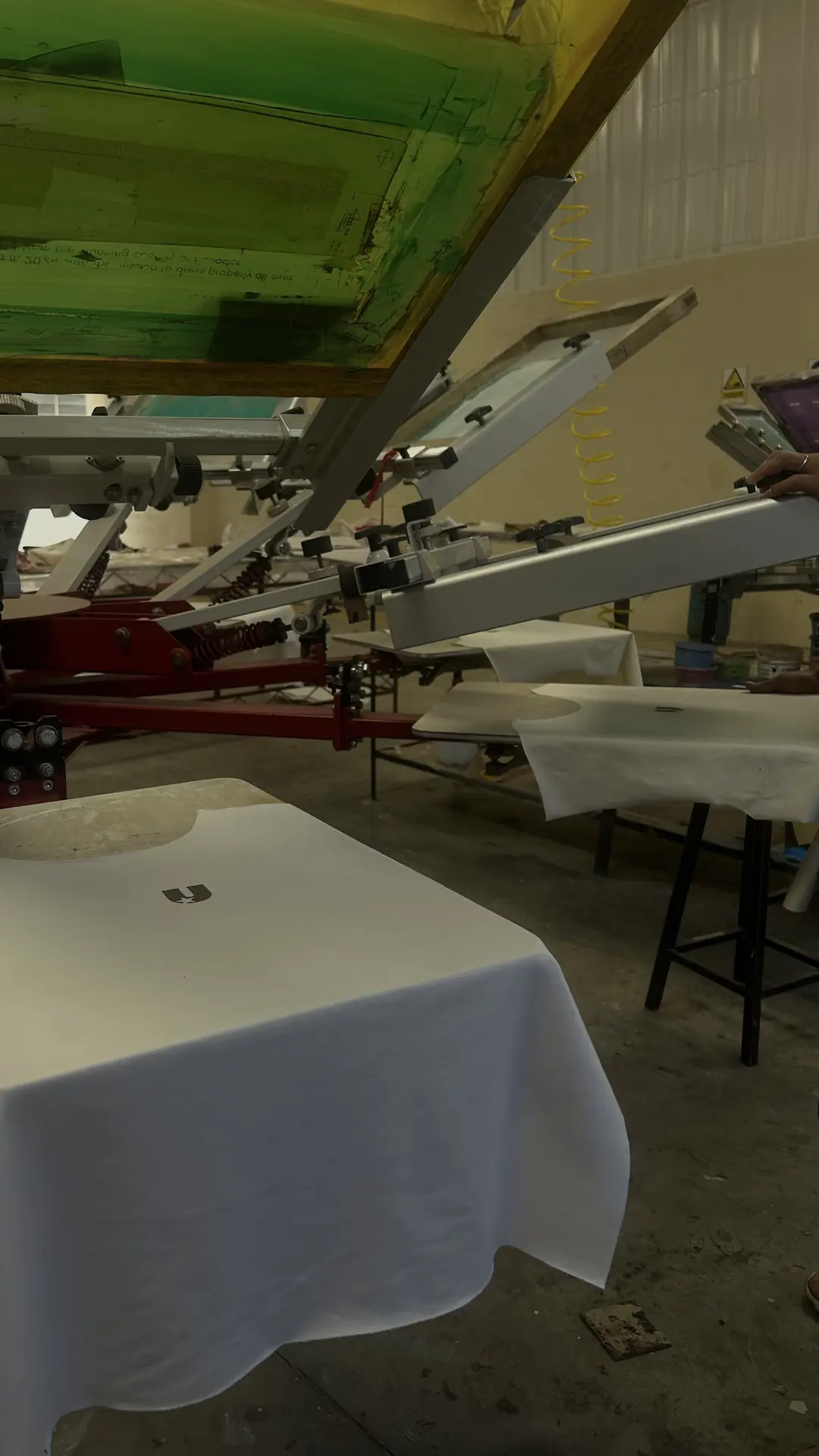 Screen printing tables in the workshop in Ecuador, a white Upper tee on the press.